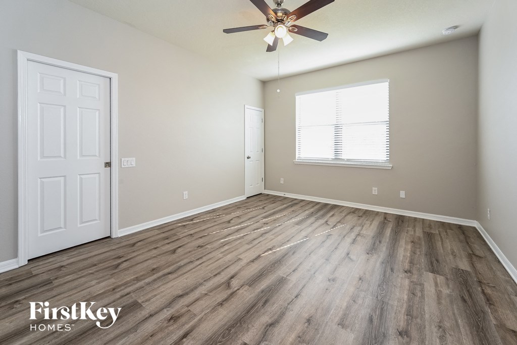 the spacious living room with hardwood floors and a ceiling fan