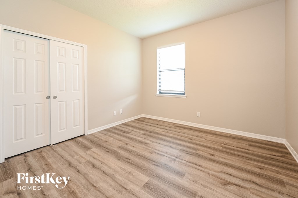 the upstairs bedroom with wood flooring and a window