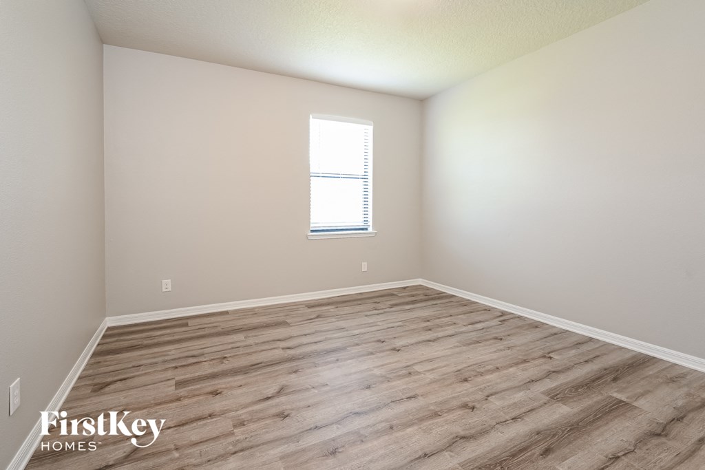 the spacious living room with wood flooring and a window