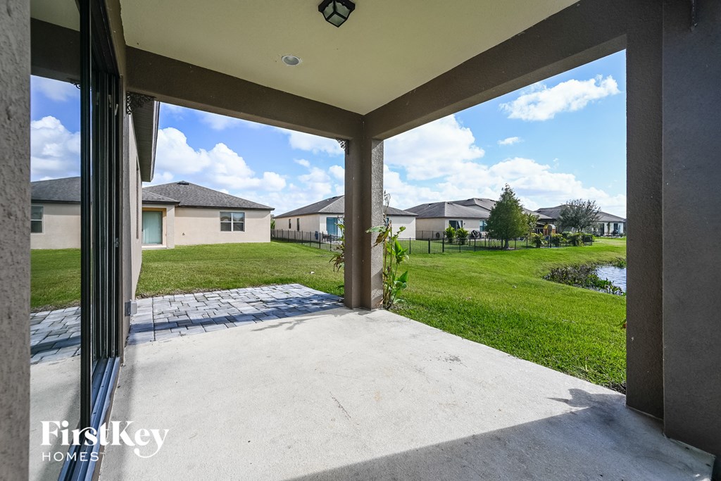 a patio with a view of the grass and houses in the background