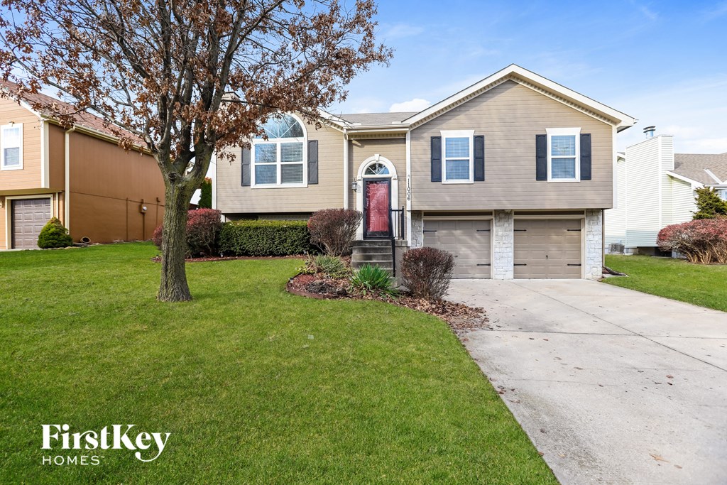 A house with a red door and a tree in front of it.
