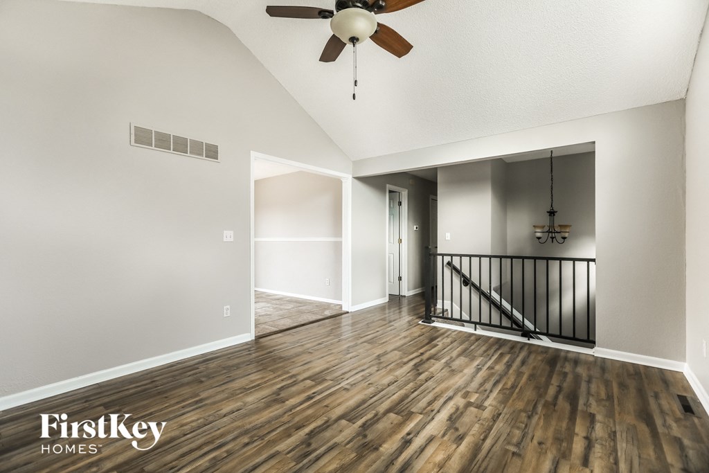 A spacious room with wooden floors and a ceiling fan.
