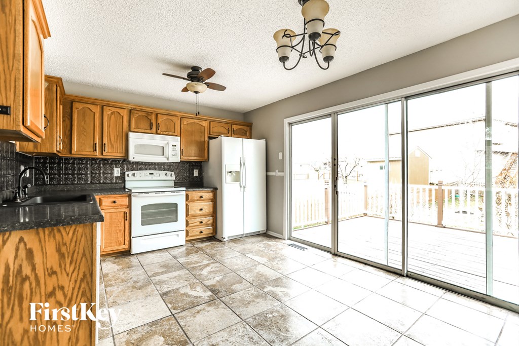 A kitchen with wooden cabinets and a black counter top.