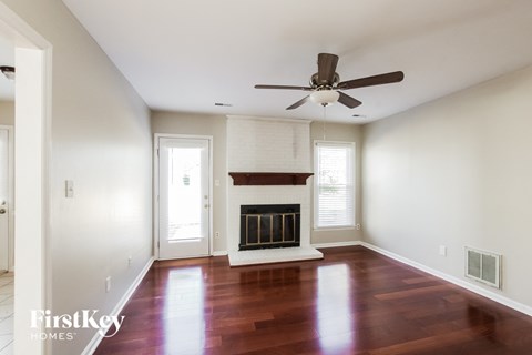 an empty living room with a fireplace and a ceiling fan