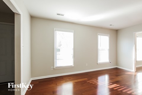 an empty living room with wood floors and two windows