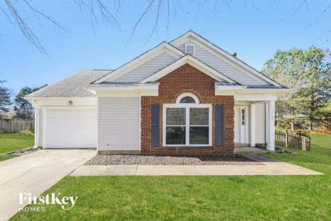 the front view of a small brick house with a front yard and grass