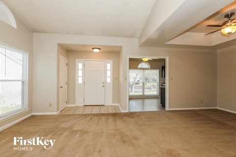 an empty living room with a white door and a ceiling fan