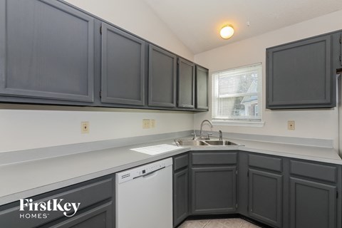 a kitchen with gray cabinets and a white dishwasher and sink