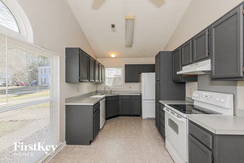 a kitchen with black cabinets and white appliances and a window