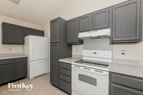 a kitchen with black cabinets and white appliances and a refrigerator