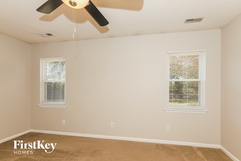 a bedroom with two windows and a ceiling fan