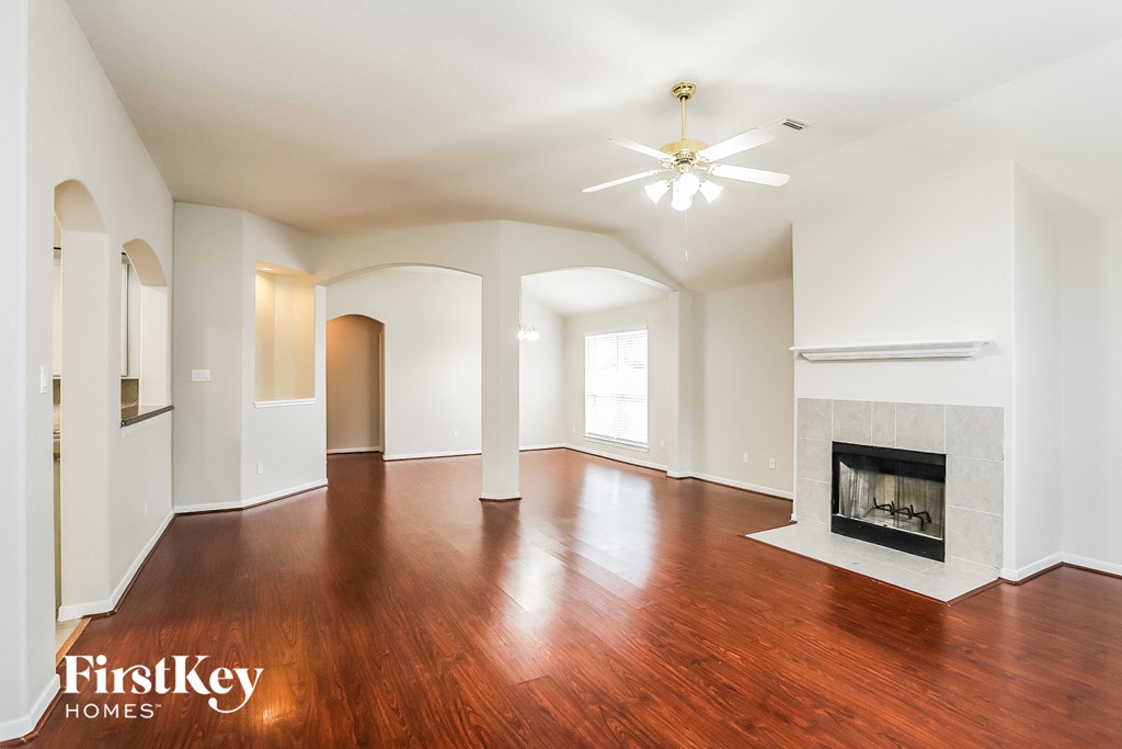 A spacious living room with a fireplace and a ceiling fan.