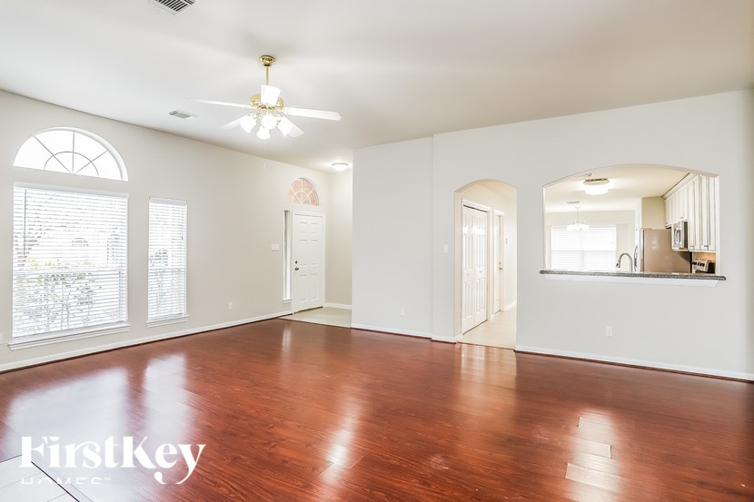 A spacious room with wooden floors and a ceiling fan.