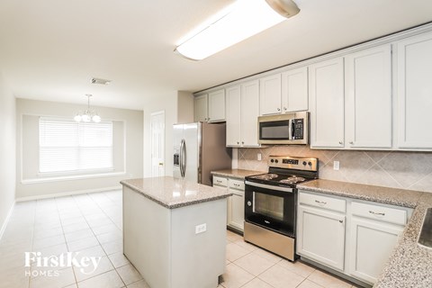 A kitchen with white cabinets and a granite countertop.