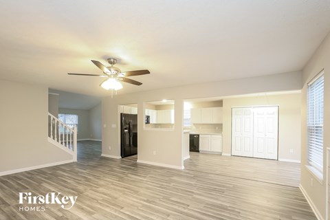 A spacious living room with a ceiling fan and lighting fixture.