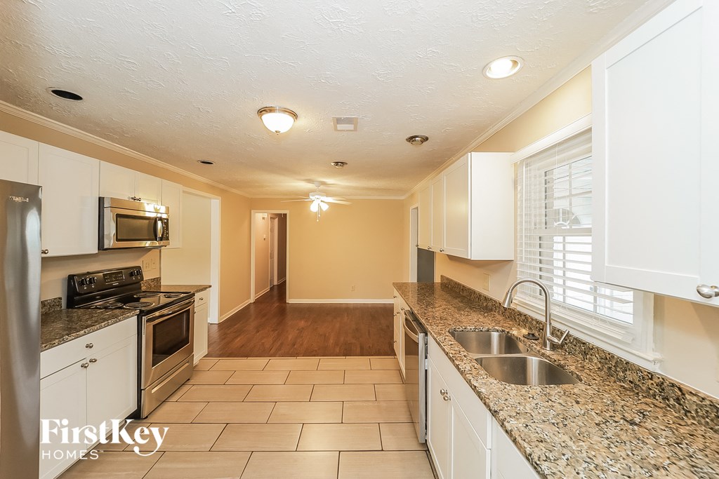 A kitchen with white cabinets and a granite counter top.