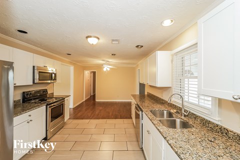 A kitchen with white cabinets and a granite counter top.
