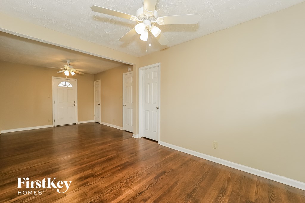 A spacious room with a ceiling fan and wooden flooring.