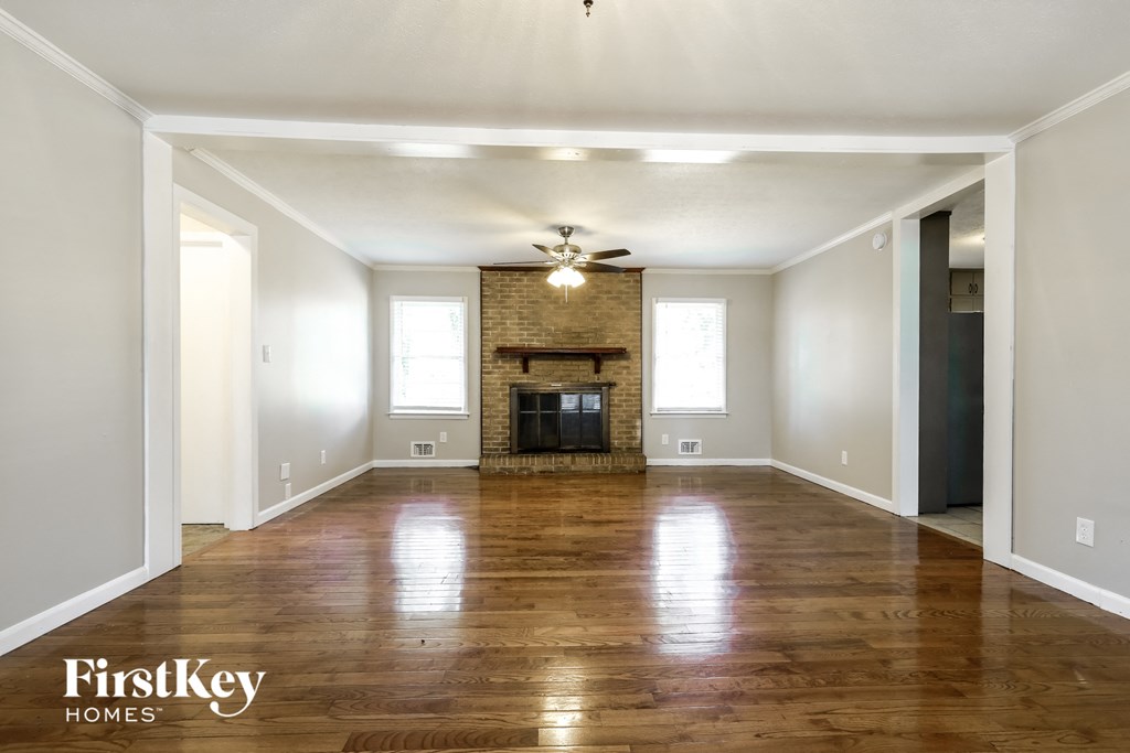 A spacious room with a fireplace and wooden floors.