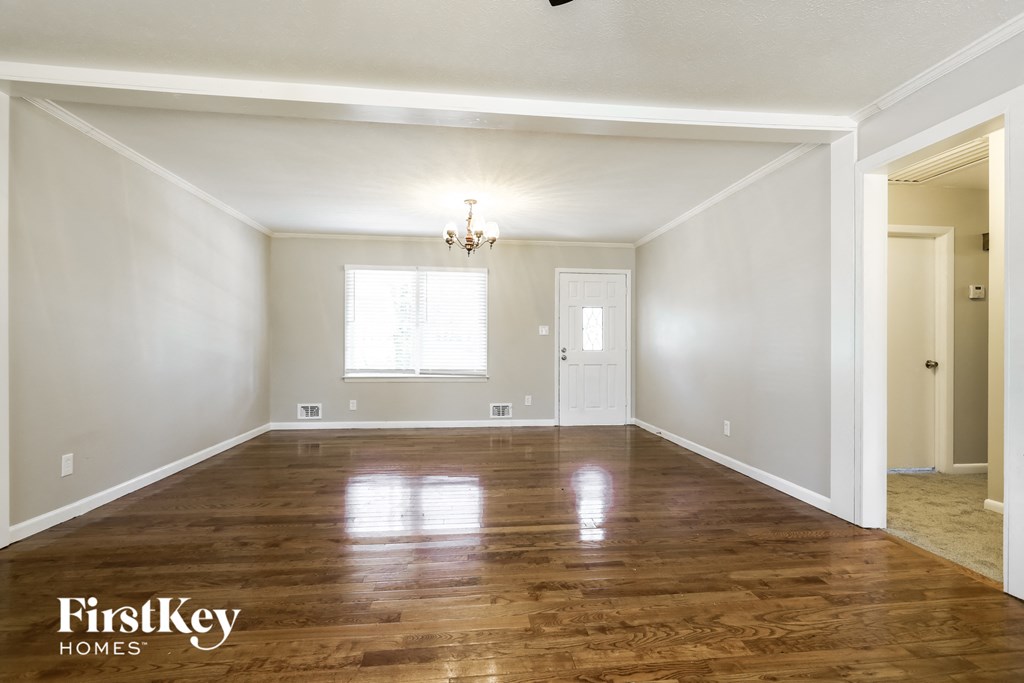 A spacious room with wooden floors and a chandelier.