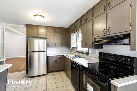 A kitchen with a stainless steel refrigerator and black stove top oven.