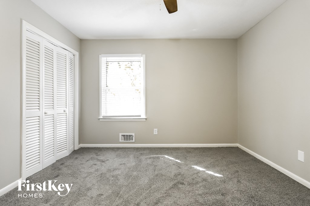A room with a window and a carpeted floor.