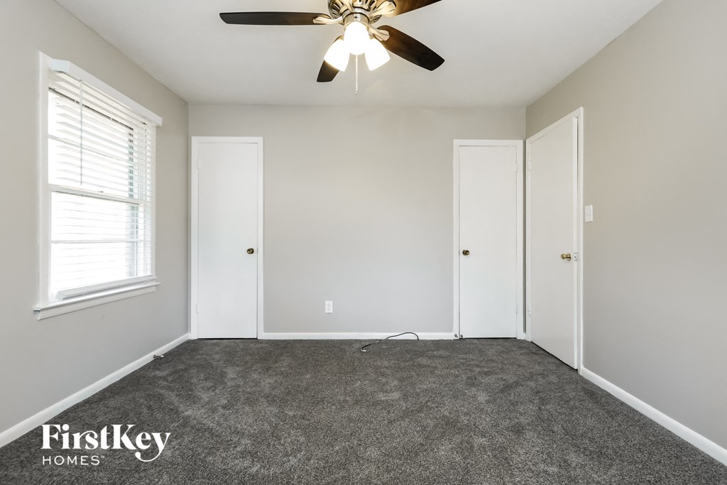 A room with a ceiling fan and three doors.