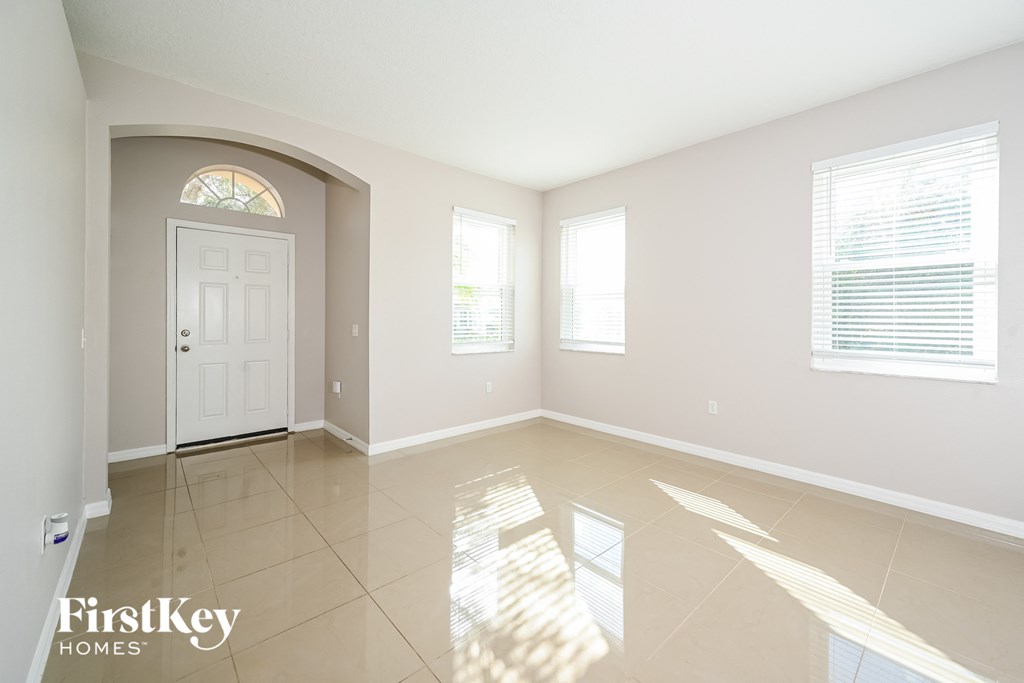 A spacious room with a white door and windows letting in natural light.