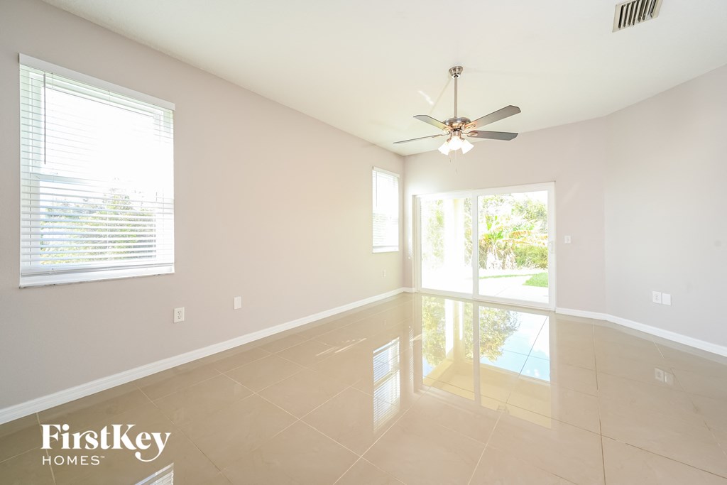A spacious room with a ceiling fan and large windows.