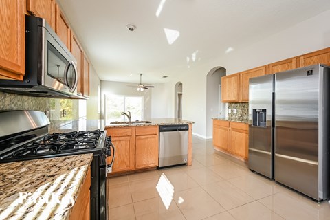 A kitchen with a black stove top oven and a black microwave above it.