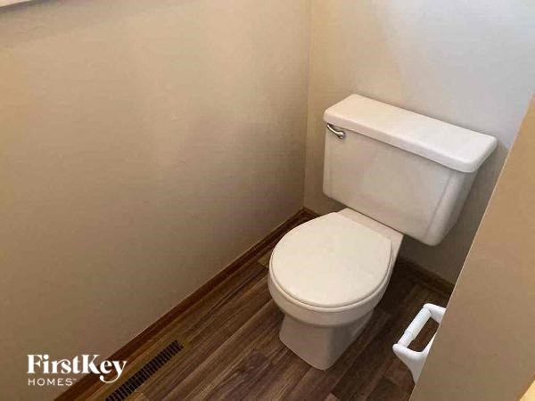 A white toilet with a white tank and a wooden floor.