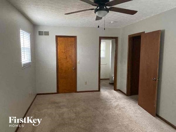 A room with a carpeted floor and a ceiling fan.