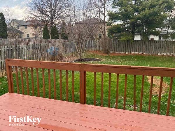 A wooden deck with a railing overlooking a yard.