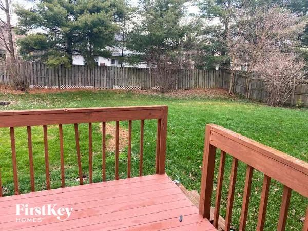 A wooden deck with a railing overlooking a grassy area.