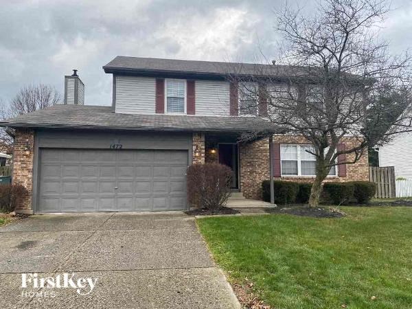 A house with a grey garage door and a brick chimney.