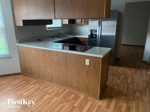 A kitchen with wooden cabinets and a stainless steel refrigerator.
