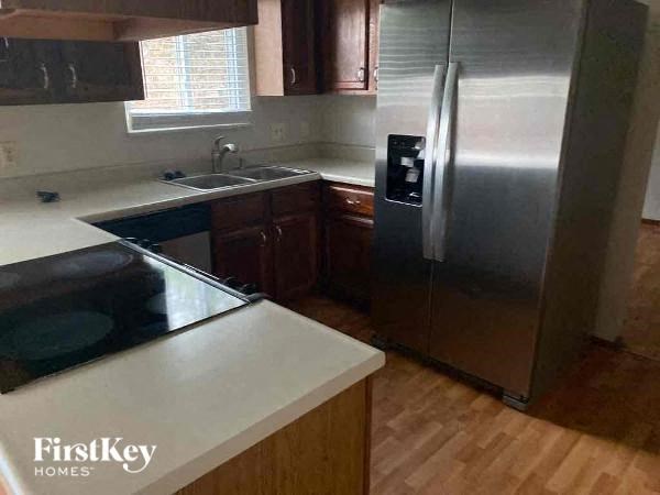 A kitchen with a stainless steel refrigerator and wooden floors.