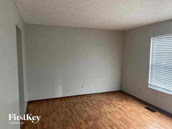 A room with wooden flooring and a window with blinds.