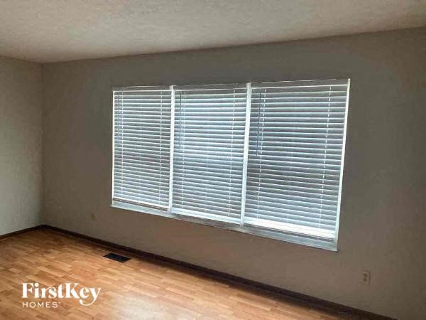 A room with a window covered in blinds and wooden flooring.