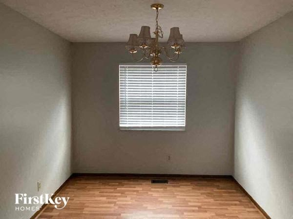A room with wooden floors and a chandelier hanging from the ceiling.