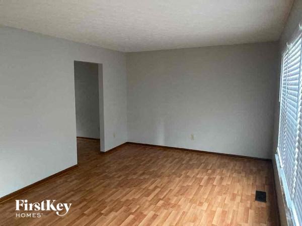 A room with wooden flooring and a doorway leading to another room.