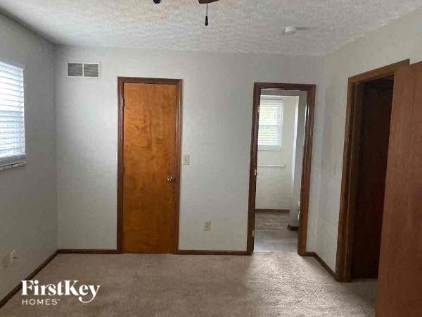 A room with a carpeted floor and a wooden door.