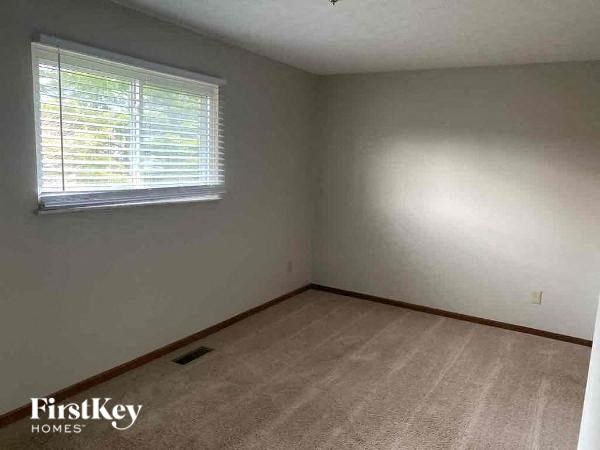 A room with a carpeted floor and a window with blinds.