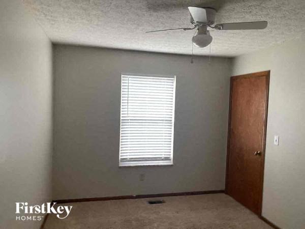 A room with a ceiling fan and a window with blinds.