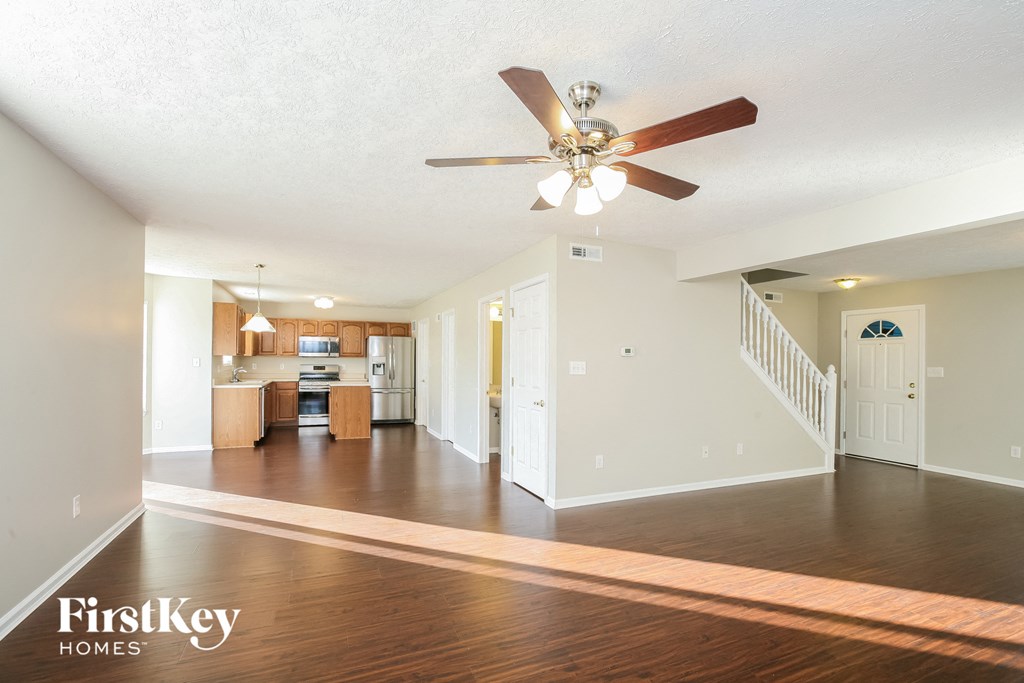 an empty living room and kitchen with a ceiling fan