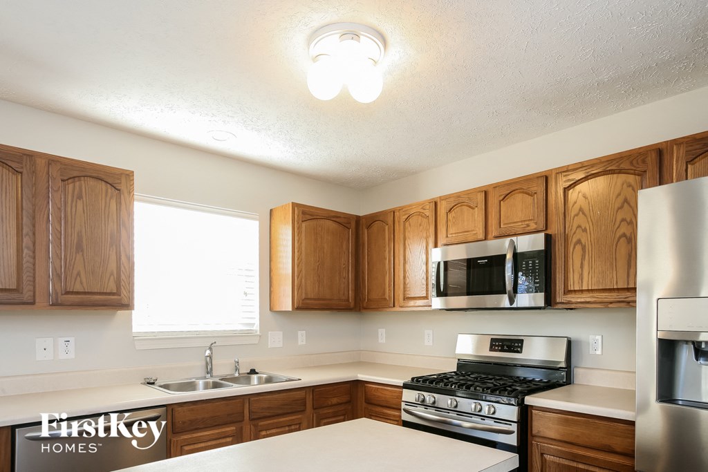 a kitchen with wooden cabinets and a stove and a microwave