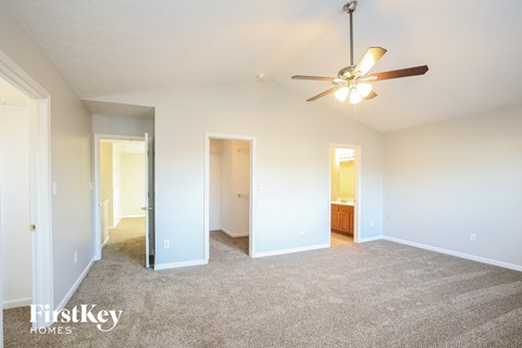a spacious living room with carpet and a ceiling fan