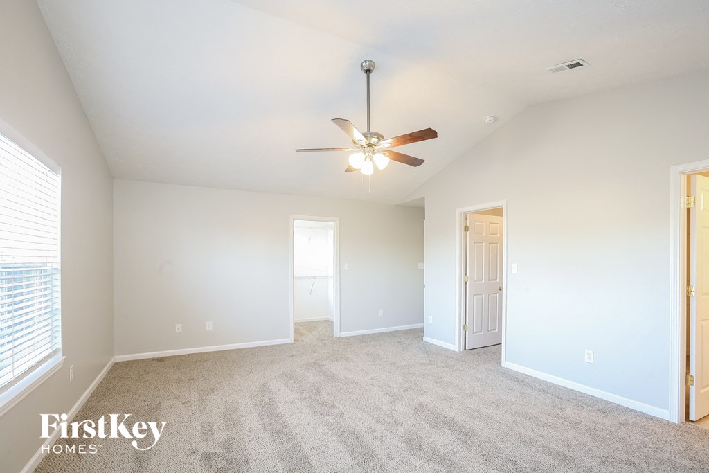 a spacious living room with carpet and a ceiling fan