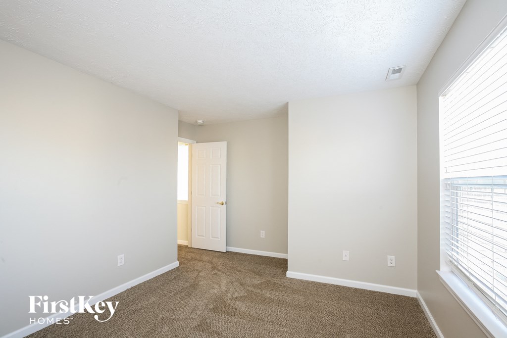 a spacious living room with carpet and a door to a closet