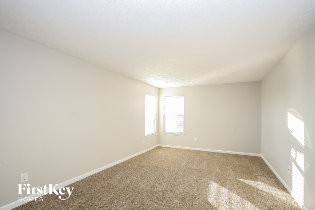 a spacious living room with carpet and a window